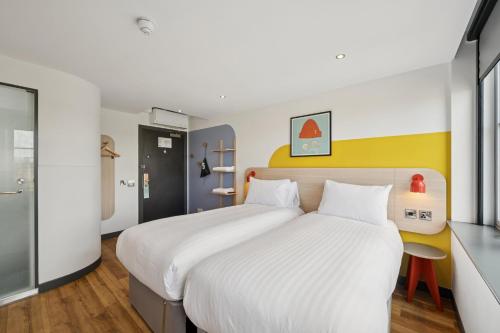 a bedroom with a large bed with white sheets at Garner Hotel Edinburgh - Haymarket by IHG in Edinburgh