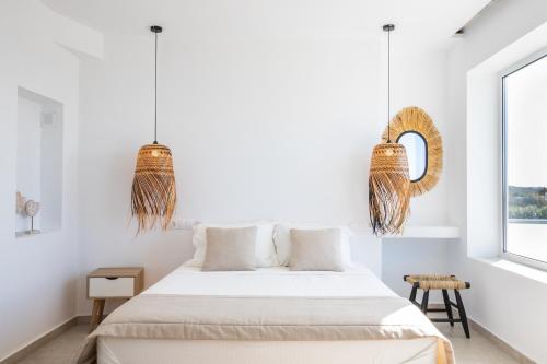 a white bedroom with a bed and a window at Arkasa Palace in Arkasa