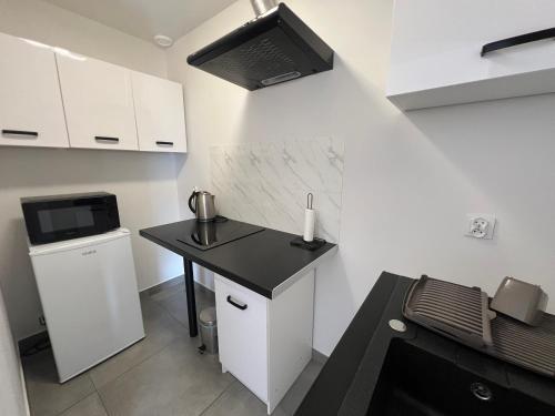 a small kitchen with a black counter and a microwave at Gościniec Solan in Jeleniów
