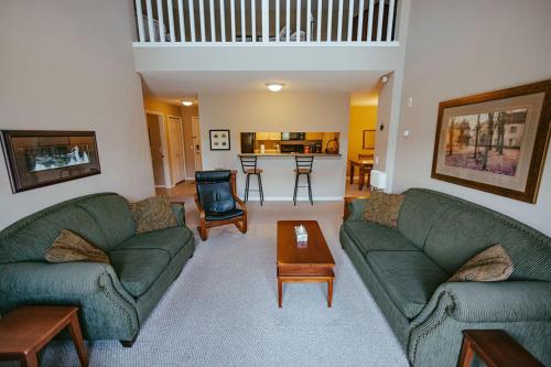 a living room with two green couches and a table at Peaks of Radium by StayIn in Radium Hot Springs
