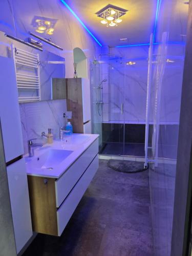 a bathroom with a sink and a shower with blue lights at Ferienwohnung Familie Lange, bis 8 Personen in Radensdorf