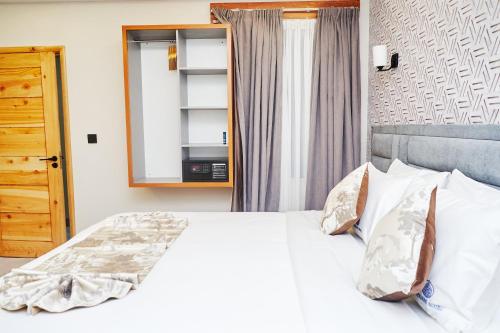 a bedroom with a white bed and a mirror at Tha Nickolee Hotel in Nanyuki