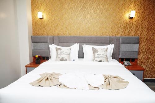 a bedroom with a large white bed with pillows at Tha Nickolee Hotel in Nanyuki