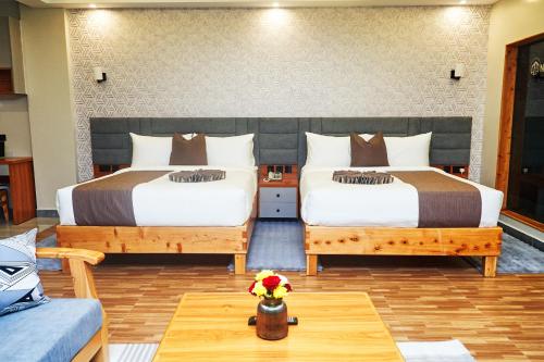 two beds in a room with a table and a couch at Tha Nickolee Hotel in Nanyuki