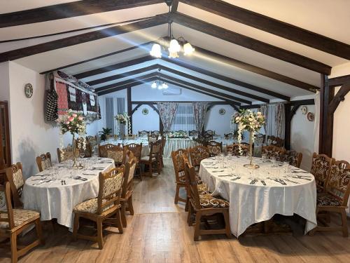 a dining room with tables and chairs with white tablecloths at Casa Dunca in Sighetu Marmaţiei