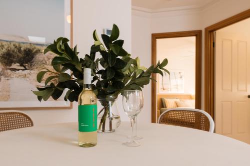 a white table with a bottle of wine and a glass at Cool beachside apartment on Jetty Road Brighton in Brighton