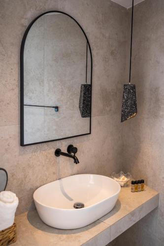 a bathroom with a white sink and a mirror at Arkasa Palace in Arkasa