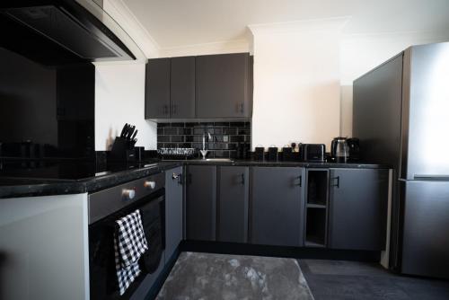 a kitchen with black and white cabinets and a refrigerator at 3BR Home Gem - sleeps 9 - Netflix - Near O2 & Greenwich Park in London