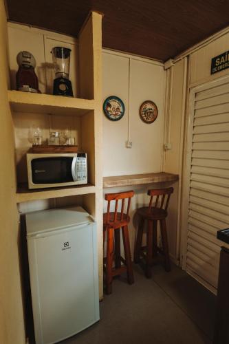 a small kitchen with two stools and a microwave at Flat Vista Mar Noronha in Fernando de Noronha