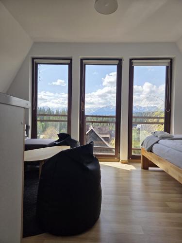 a bedroom with a bed and a table and windows at Natura Bukowina Tatrzańska in Bukowina Tatrzańska