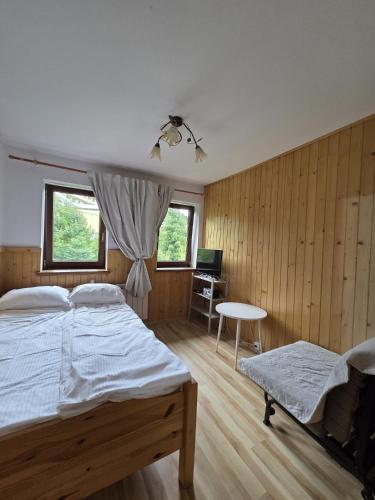 a bedroom with a bed and a table and a desk at Natura Bukowina Tatrzańska in Bukowina Tatrzańska