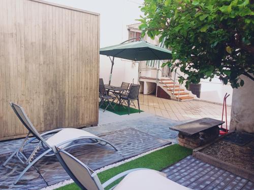 a patio with an umbrella and chairs and a table at Il giardino in città Savona in Savona