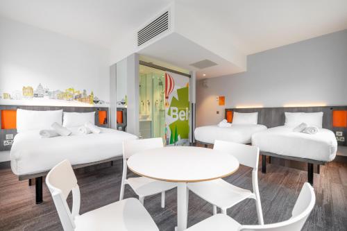 a room with three beds and a table and chairs at easyHotel Belfast in Belfast