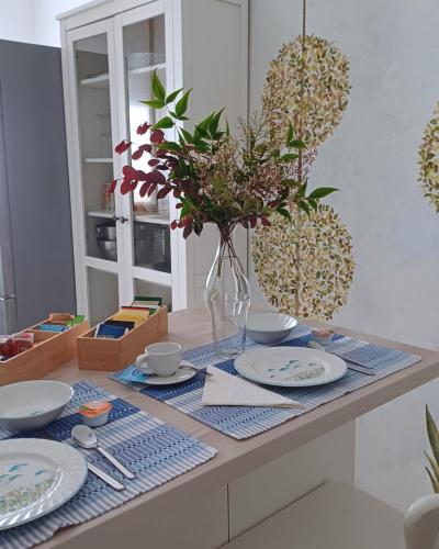 a table with plates and a vase with flowers on it at Le Jardin Secret in Milan