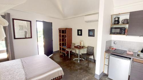 a room with a bed and a table and a kitchen at La Case des Caraïbes in Le Gosier