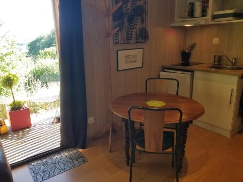 une cuisine avec une table et deux chaises à côté d'une fenêtre dans l'établissement Le petit paradis, mini maison,nature,confort,calme, à Saint-Julien-le-Petit