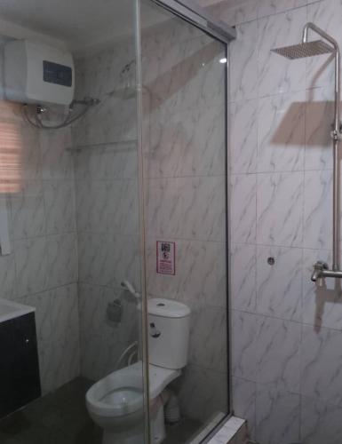 a bathroom with a toilet and a glass shower at DND Apartments in Benin City