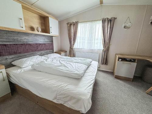 洛斯托夫特Homely Caravan With Decking And Wifi In Lowestoft Ref 12097B的卧室里有一张铺着白色床单的大床