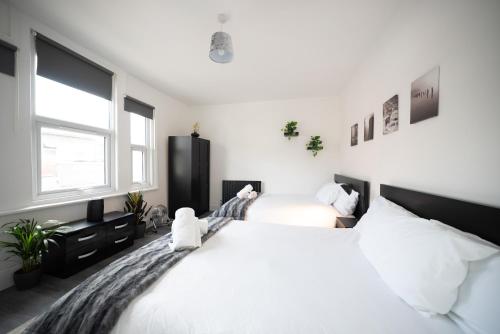 two beds in a bedroom with white walls and windows at 3BR Home Gem - sleeps 9 - Netflix - Near O2 & Greenwich Park in London