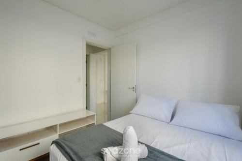 a bedroom with a white bed and a window at Apt c/ Churrasq. a 600m da Praia GEN0102 in Balneário Camboriú