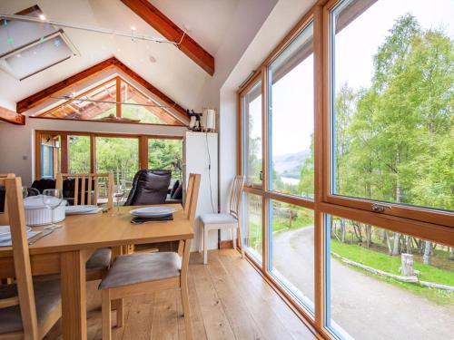 a dining room with a table and large windows at Rathad An Drobhair in Garve