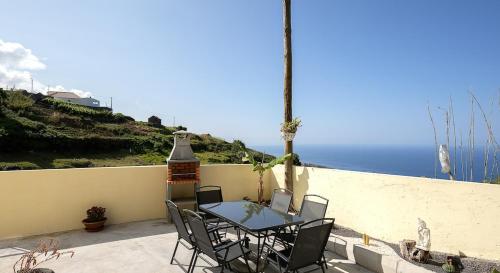 a table and chairs on a balcony with the ocean at Franco's House II, Mar e Serra in Estreito da Calheta