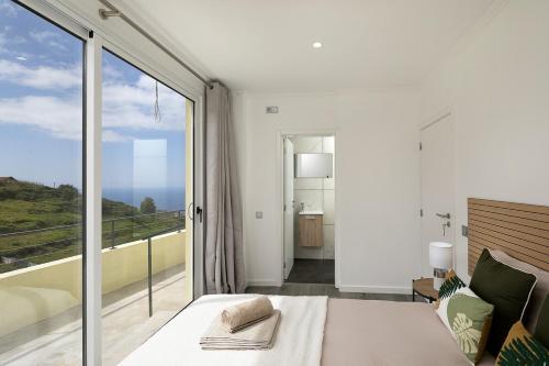 a bedroom with a bed and a large window at Franco's House II, Mar e Serra in Estreito da Calheta