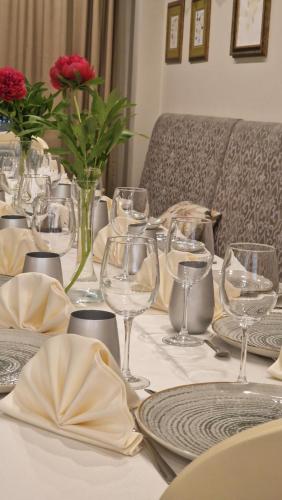 a table with glasses and plates and flowers on it at PENSIUNEA DIMITRIOS Relaxare cu jacuzzi pe Valea Cernei in Băile Herculane