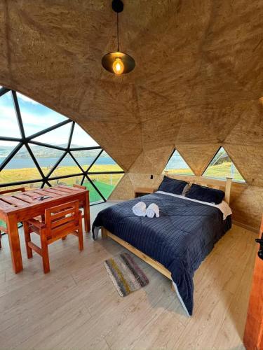 a bedroom with a bed and a wooden table at San Jerónimo Glamping in Tota