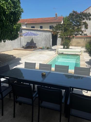 une table et des chaises devant une piscine dans l'établissement Maison Pamplemousse, à Arles