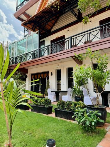 a house with white chairs and plants in a yard at Activate C3 Hostel in Phnom Penh
