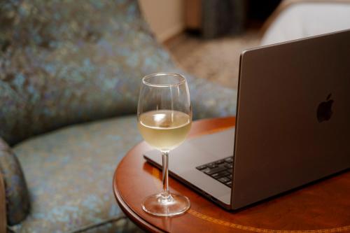 a glass of wine next to a laptop on a table at Le Cedrus Hotel in Al Arz