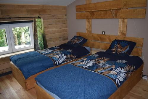 two beds in a bedroom with wooden walls at Gite cocon dans la forêt in Philippeville