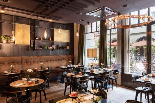 a restaurant with tables and chairs and a large window at NH Bern The Bristol in Bern