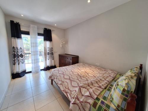 a bedroom with a bed and a dresser and windows at Forest View Apartments in Kololi