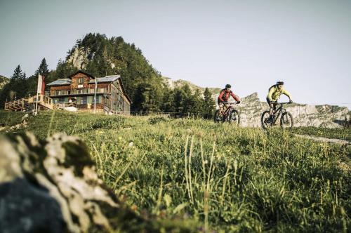 two people riding bikes on a hill with a house at COLORGRAM Loft - Colorful Design Apartment in Tyrol, presented by AlpenLuxus in Kramsach