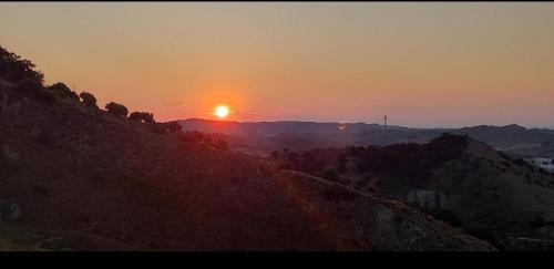 a sunset on a hill with the sun setting in the distance at L'Aurora Corso Umberto l 220, 88821 Rocca di Neto in Rocca di Neto
