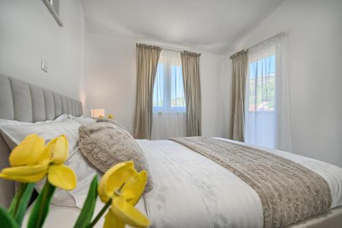 a white bedroom with a bed with yellow flowers at Relax penthouse private jacuzzi Split area in Žrnovnica