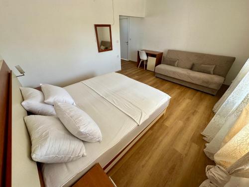 a bedroom with a bed with white pillows and a couch at Villa Paris in Donji Štoj
