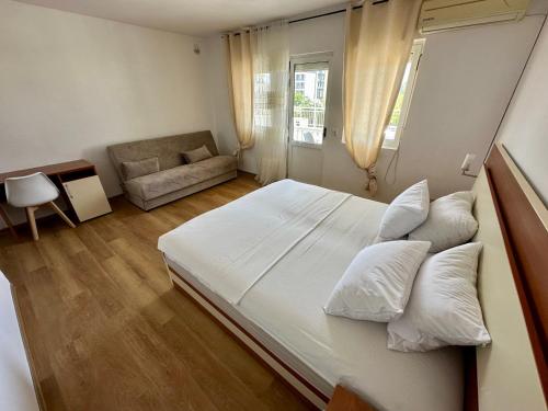 a bedroom with a large white bed and a couch at Villa Paris in Donji Štoj