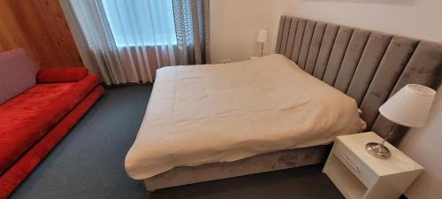 a small bedroom with a bed and a red couch at Asnyk Prestige Apartments in Kraków
