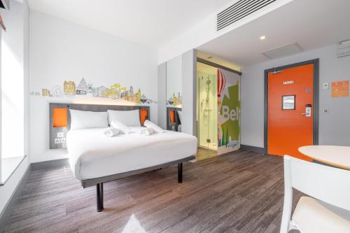 a bedroom with a white bed and an orange door at easyHotel Belfast in Belfast