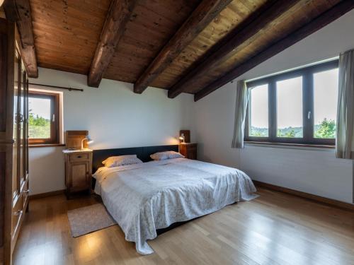 a bedroom with a large bed and two windows at Apartment Purin I by Interhome in Murazzano