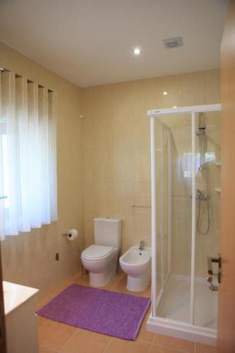 a bathroom with a toilet and a glass shower at Casa Aido in Junqueira