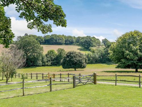a wooden fence in a field with trees at Castlemans Stables East in Sedlescombe