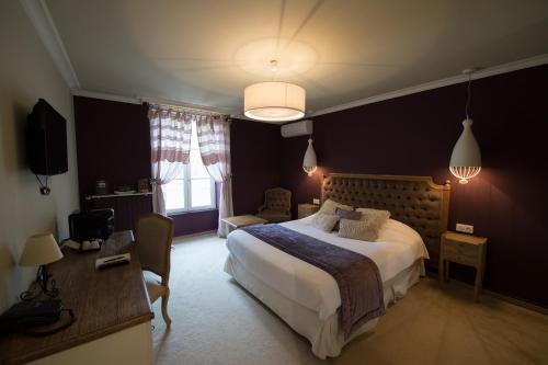 a bedroom with a large bed and a desk at Chateau du Clos de la Ribaudiere - Teritoria in Chasseneuil-du-Poitou