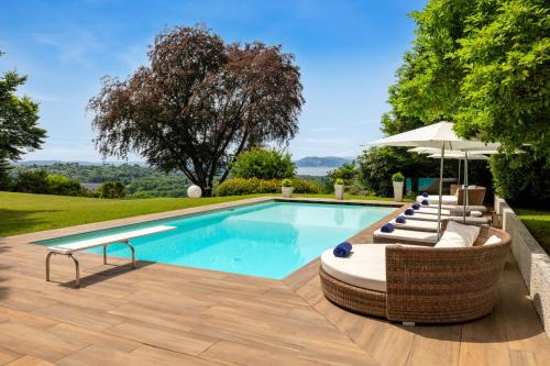 una piscina con sillas y sombrilla en Villa Serenity, en Besozzo