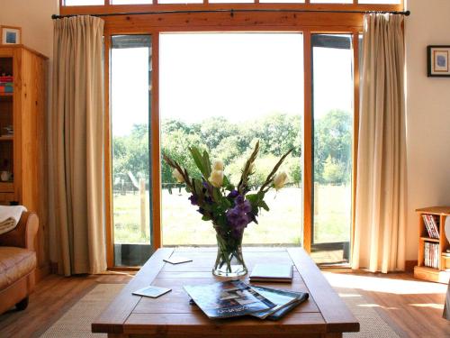 eine Vase mit Blumen auf einem Tisch im Wohnzimmer in der Unterkunft The Barn At Fishponds in Brook