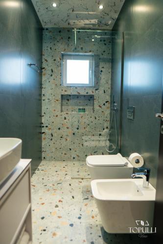 a bathroom with a toilet and a sink and a window at Villa Topulli View in Gjirokastër