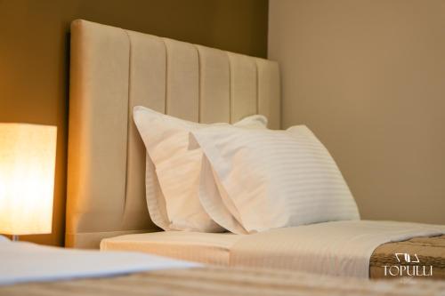 a bed with a white headboard with pillows on it at Villa Topulli View in Gjirokastër